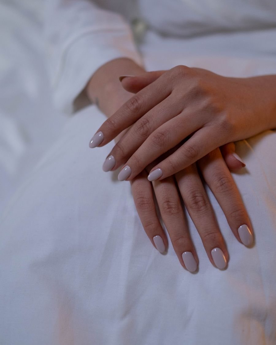 Elegante Nude-Gelnägel in Mandelform auf weißem Leinen